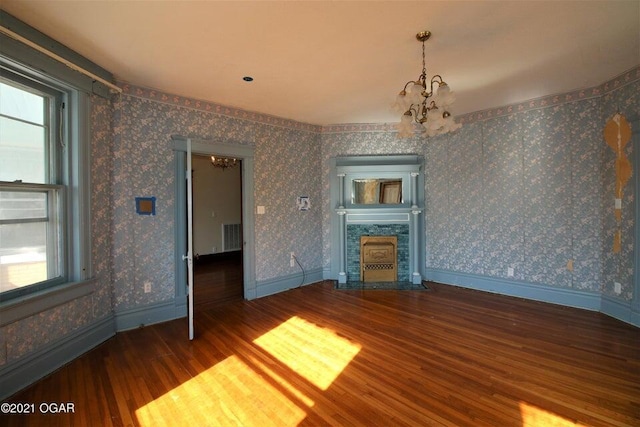 unfurnished living room featuring a wealth of natural light, a notable chandelier, and wood-type flooring