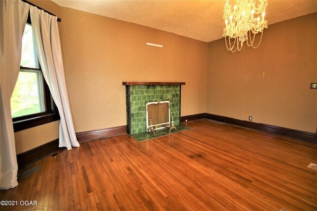 unfurnished living room featuring hardwood / wood-style floors, a fireplace, and a chandelier