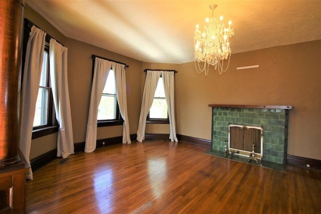 unfurnished living room featuring a notable chandelier, a fireplace, and wood-type flooring