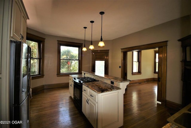 kitchen featuring decorative light fixtures, white cabinets, fridge, dark stone countertops, and black range with gas cooktop