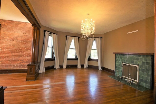 unfurnished living room with a tile fireplace, a textured ceiling, a chandelier, and dark hardwood / wood-style flooring