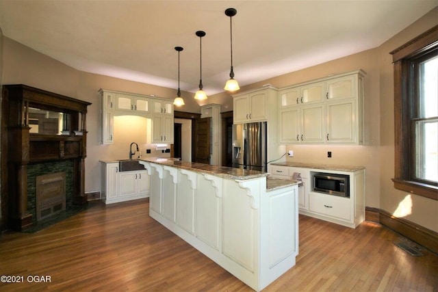 kitchen with stainless steel appliances, light stone countertops, hanging light fixtures, and a center island