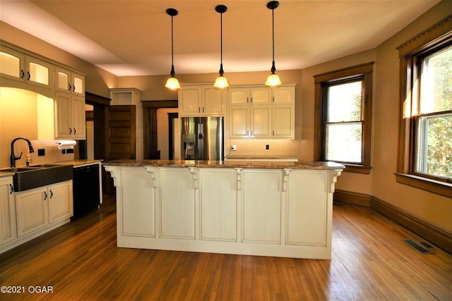 kitchen featuring dishwasher, decorative light fixtures, stainless steel fridge, a kitchen island, and sink