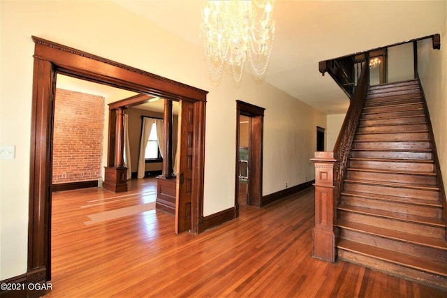 stairway with hardwood / wood-style floors and a chandelier