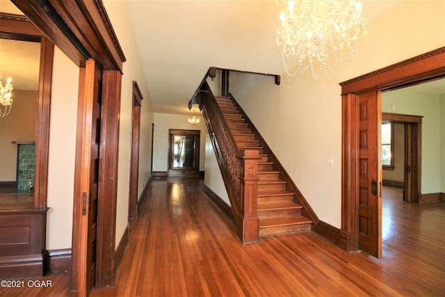 staircase with a notable chandelier and wood-type flooring