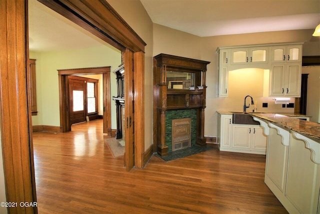 kitchen featuring sink, white cabinetry, light stone countertops, and dark wood-type flooring