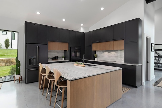 kitchen featuring black appliances, a kitchen island, lofted ceiling, backsplash, and sink