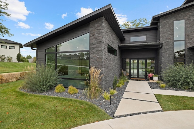 view of exterior entry with a lawn and french doors