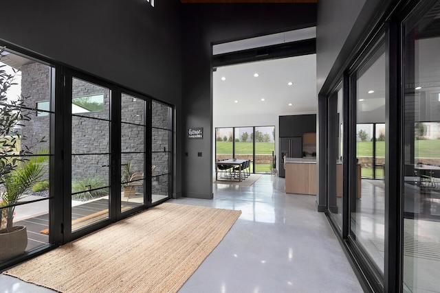 entryway with finished concrete flooring, a high ceiling, and recessed lighting