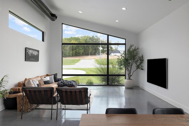 living room featuring finished concrete flooring, recessed lighting, and baseboards