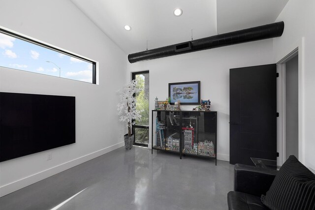 living room with a high ceiling and concrete floors