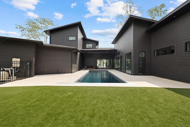 back of property with a yard, an outdoor pool, and a patio