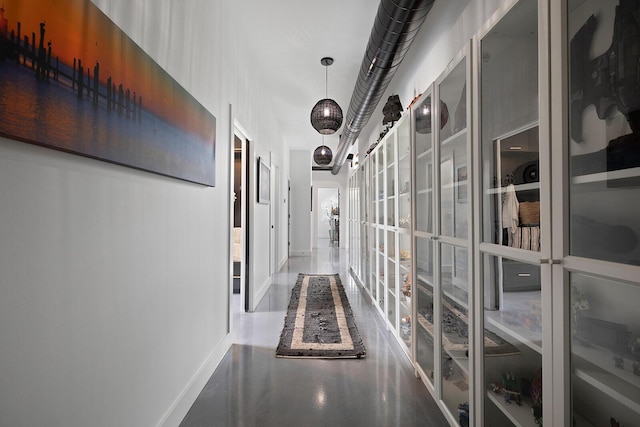 hall with finished concrete flooring and baseboards