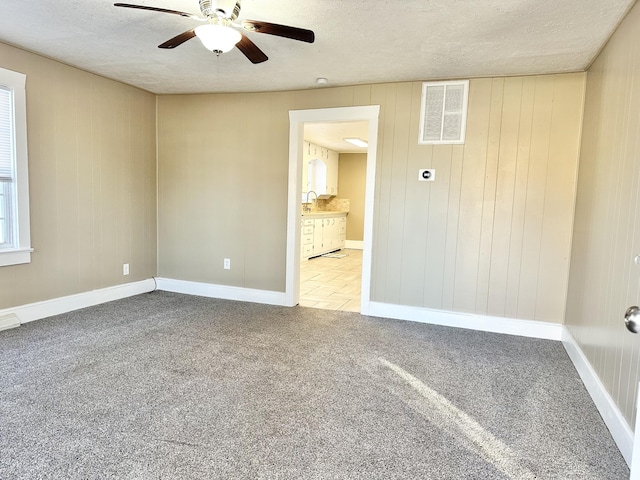 empty room with ceiling fan, carpet, and a textured ceiling