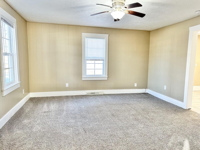 empty room with a textured ceiling, ceiling fan, and carpet floors