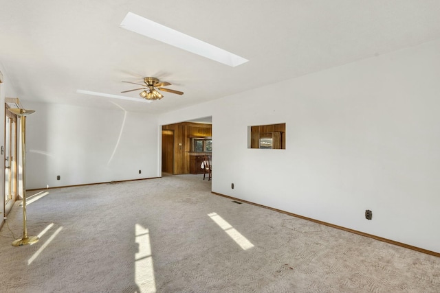 spare room featuring ceiling fan, a skylight, and light carpet