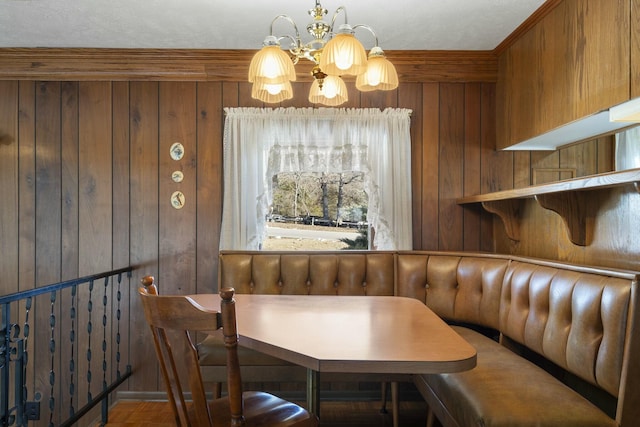 dining space with wood walls, crown molding, breakfast area, and a notable chandelier