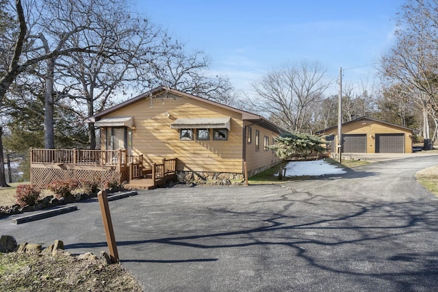 view of side of home with a wooden deck, a garage, and an outdoor structure