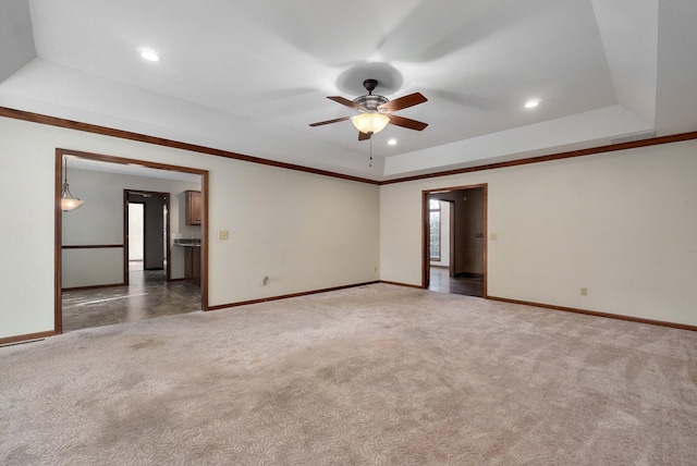 unfurnished room with ceiling fan, dark carpet, and a raised ceiling