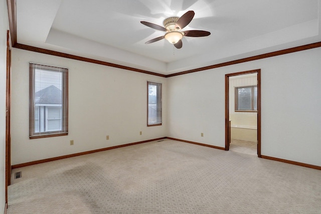 carpeted spare room featuring ceiling fan and a raised ceiling