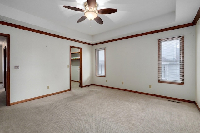 unfurnished room featuring ceiling fan, light colored carpet, plenty of natural light, and a raised ceiling