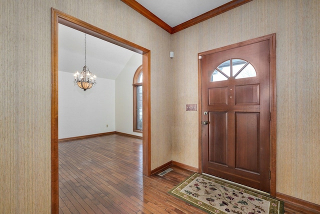 foyer with a notable chandelier, ornamental molding, and hardwood / wood-style floors