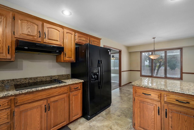 kitchen featuring black appliances, light stone countertops, and pendant lighting