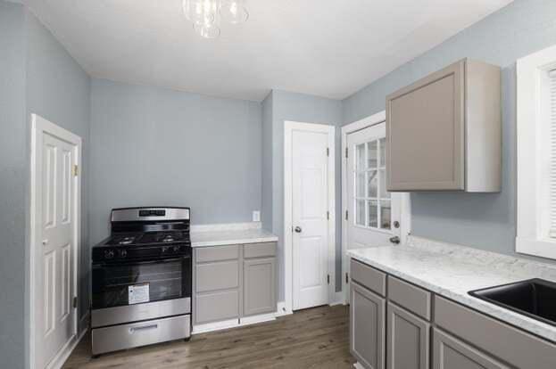 kitchen featuring sink, gray cabinets, stainless steel range with gas cooktop, and dark hardwood / wood-style floors