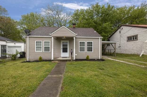 bungalow featuring a front lawn and a carport