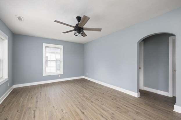 unfurnished room with ceiling fan, wood-type flooring, and plenty of natural light