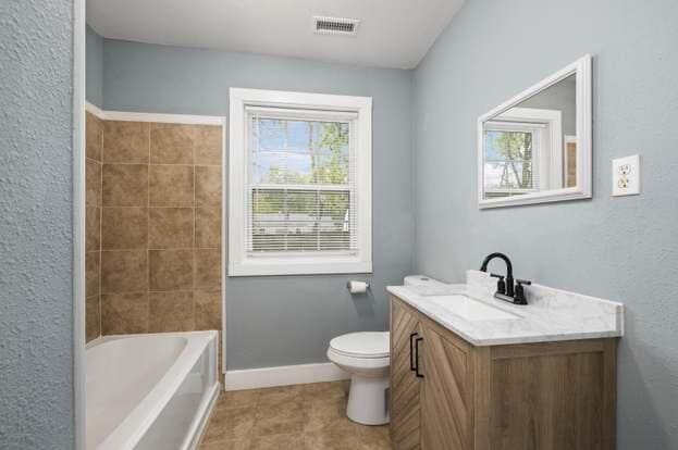 full bathroom with toilet, vanity, a healthy amount of sunlight, and shower / bath combination