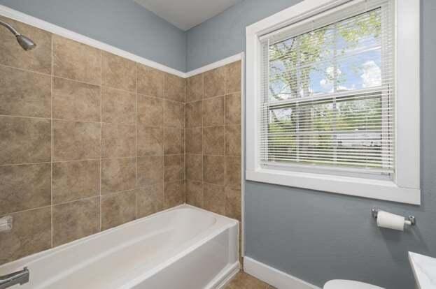 bathroom featuring toilet and tiled shower / bath combo