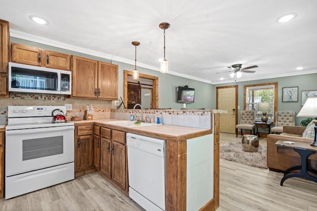 kitchen featuring white appliances, decorative light fixtures, kitchen peninsula, light wood-type flooring, and crown molding