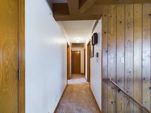 hallway featuring light carpet and wood walls