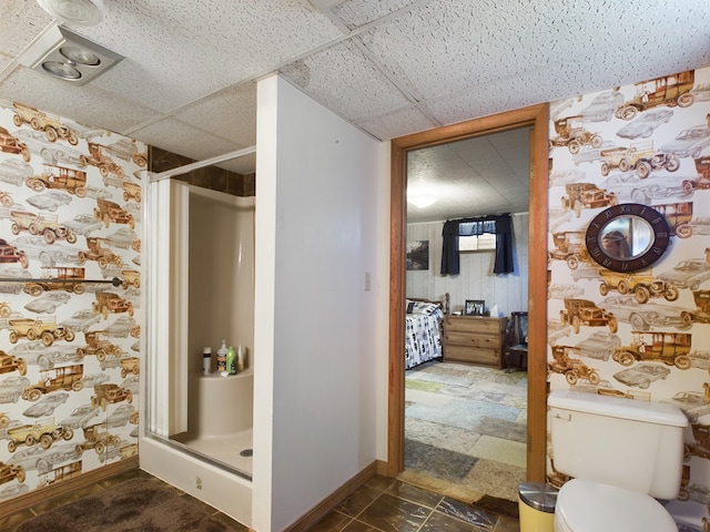 bathroom featuring a paneled ceiling, walk in shower, and toilet