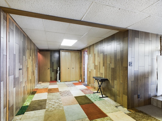 basement with wooden walls and a drop ceiling