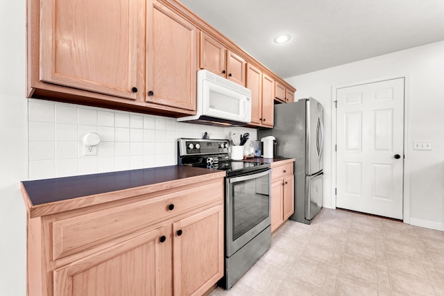 kitchen featuring stainless steel appliances, light brown cabinetry, and backsplash