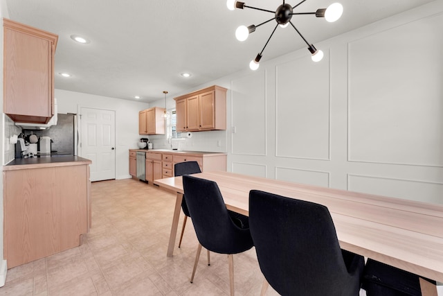 interior space with decorative light fixtures, light brown cabinets, stainless steel appliances, sink, and a chandelier