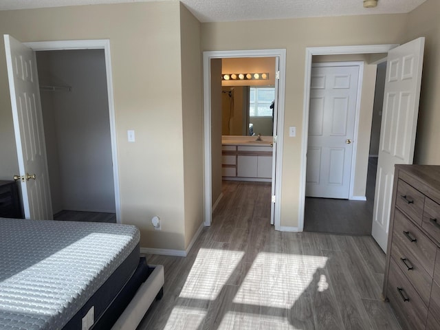 bedroom featuring ensuite bathroom, a closet, a textured ceiling, and wood-type flooring