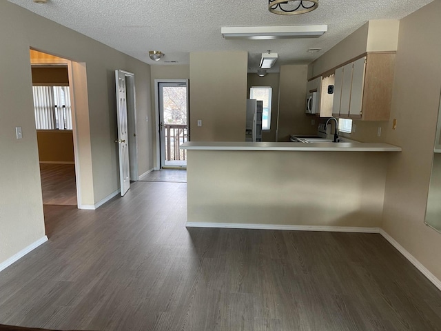 kitchen featuring kitchen peninsula, dark wood-type flooring, a textured ceiling, and stainless steel appliances