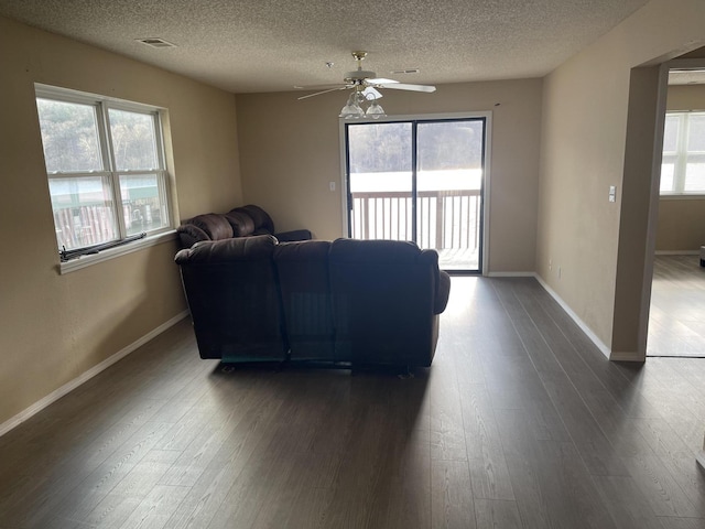 living room featuring a textured ceiling, ceiling fan, and dark hardwood / wood-style floors