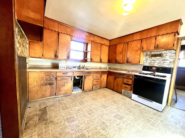 kitchen featuring gas range oven, tasteful backsplash, and sink