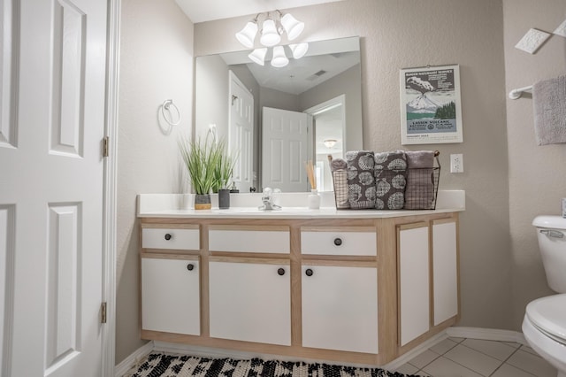 bathroom with toilet, tile patterned flooring, an inviting chandelier, and vanity