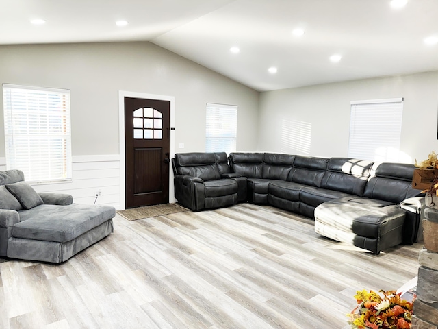 living room with a wealth of natural light, vaulted ceiling, and light hardwood / wood-style flooring