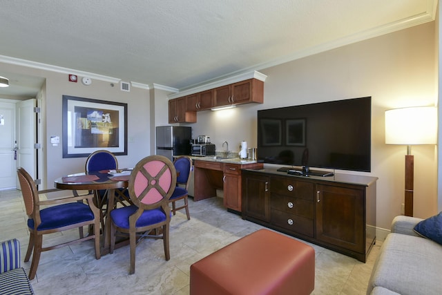 kitchen with ornamental molding, a textured ceiling, and stainless steel refrigerator