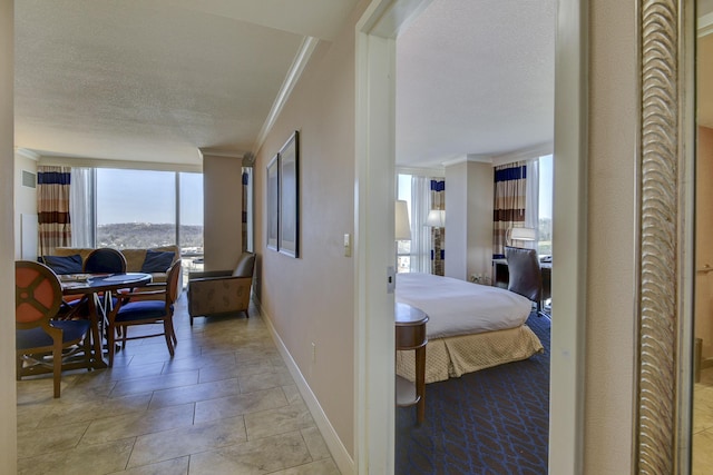 hall with floor to ceiling windows, a textured ceiling, ornamental molding, and light tile patterned floors