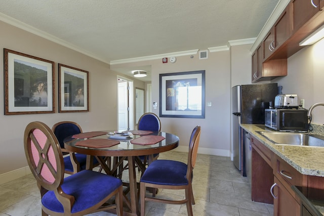 tiled dining room featuring sink, a textured ceiling, and crown molding