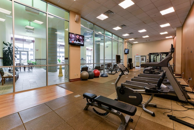 gym featuring a paneled ceiling, wood-type flooring, and floor to ceiling windows