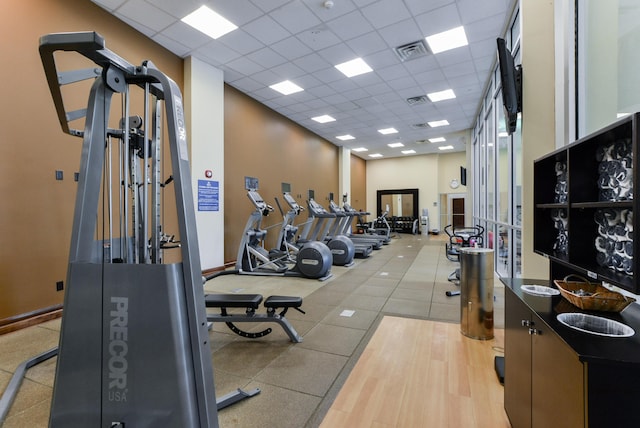 gym with light wood-type flooring and a paneled ceiling