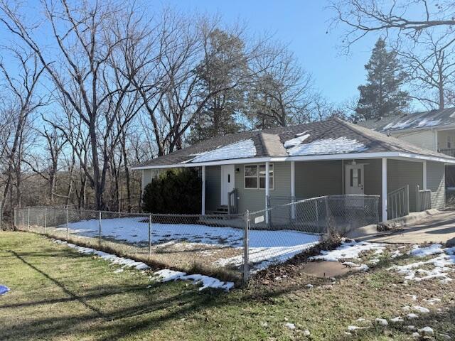 snow covered back of property featuring a lawn